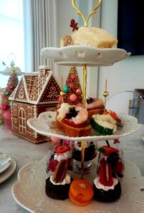 Tiered serving stand with tea sandwiches, shrimp crostini, macarons, and petite desserts at a holiday ladies tea catered by Culinary Productions.