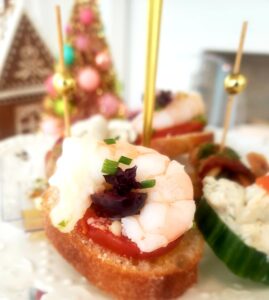 Close-up of shrimp crostini topped with fresh herbs, served as part of a holiday ladies tea catering display.