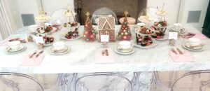 Elegant holiday ladies tea table setup with tiered trays, tea cups, gingerbread décor, and catered desserts.