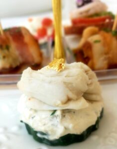 Close-up of shrimp crostini topped with fresh herbs, served as part of a holiday ladies tea catering display.